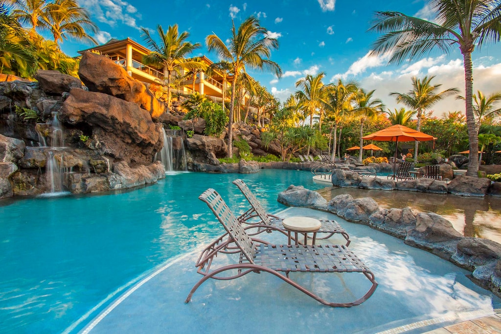 A serene pool with waterfall and Jacuzzis creates a resort feel