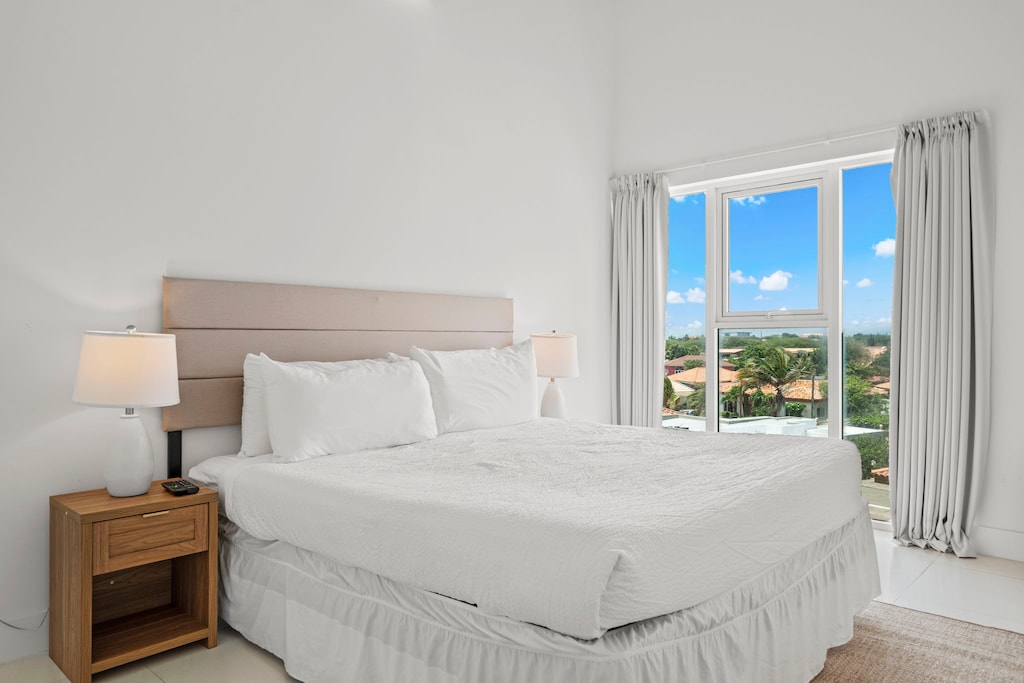 Drift into restful sleep in this serene and spacious bedroom with natural light - Unwind with the comfort of a plush queen size bed and a view of the surroundings - A peaceful retreat equipped with modern touches like a wall-mounted smart TV