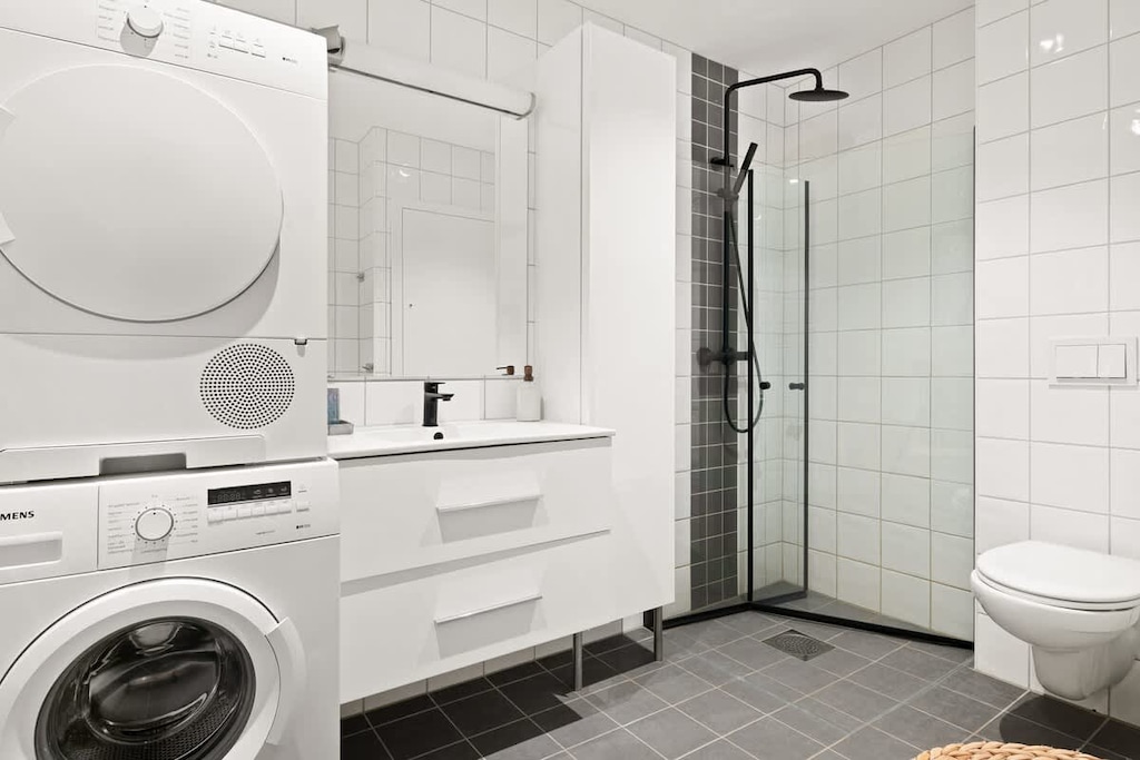 Stilfullt svart-hvitt bad med to dusjhoder for en luksuriøs opplevelse.
Fullt utstyrt med vaskemaskin, tørketrommel og flere praktiske fasiliteter.