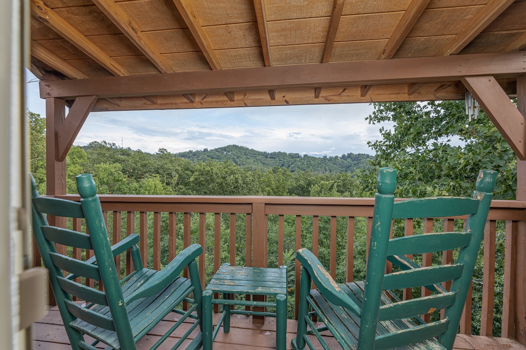 Green rocking chairs on a covered deck at Bearing Views, a 3 bedroom cabin rental located in Pigeon Forge