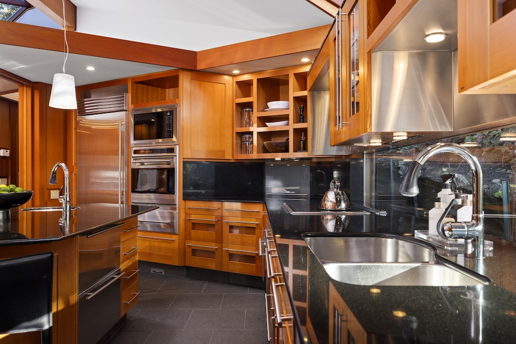 Sleek modern kitchen with black granite countertops and warm wood cabinetry.