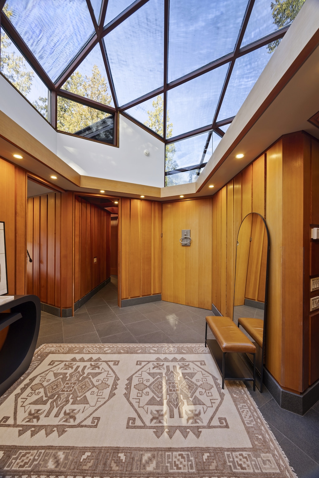 Spacious hallway with wood paneling and a geometric skylight.