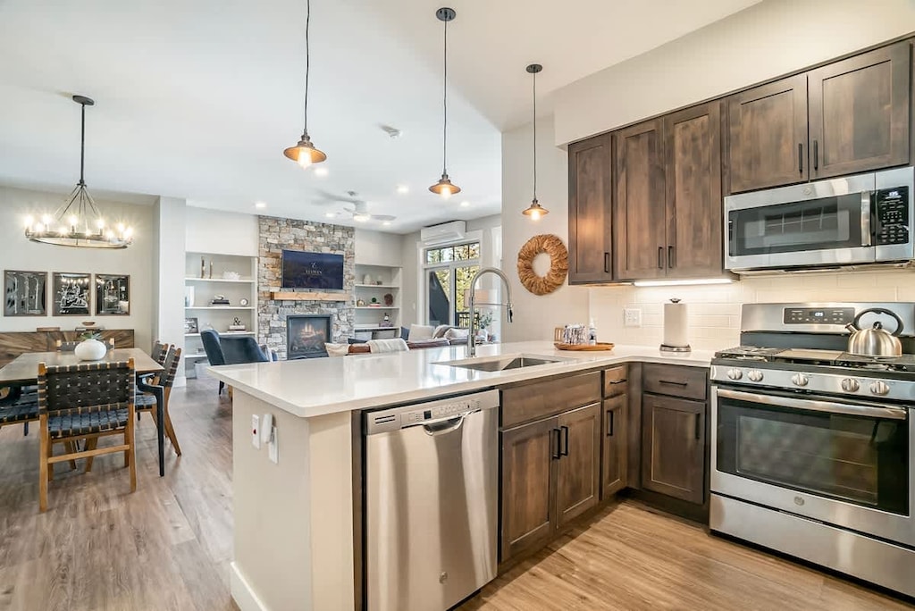 Bright open-concept kitchen with stainless steel appliances, island seating, and dining for 6—flowing seamlessly into the cozy living room.