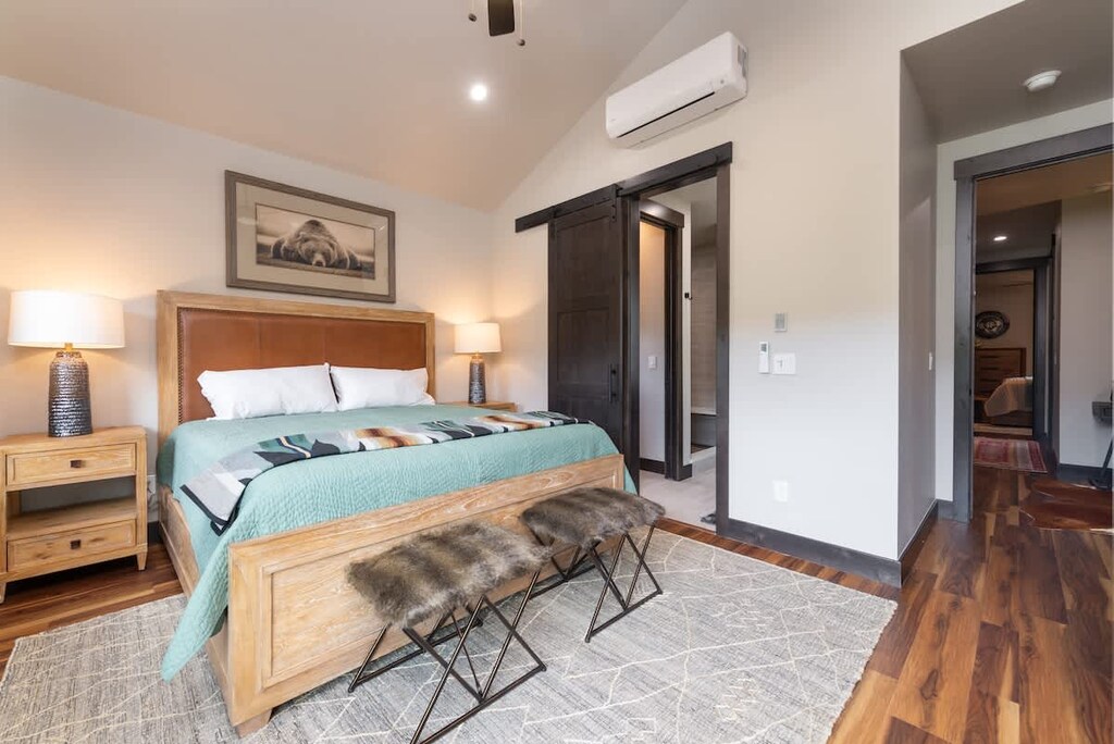 - Rest easy in the inviting bedroom with a cozy bed, plush fur benches, and soft lighting
- Slide open the rustic barn door to your private ensuite bathroom oasis
- Wake up to scenic mountain mornings and hardwood floor charm