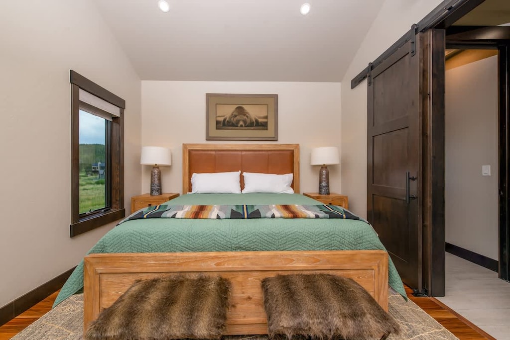 - Rest easy in a king sized bed framed by rustic wood and calming green tones
- Slide open the dark barn door to reveal a private ensuite retreat
- Wake to soft morning light and forest views through windows

