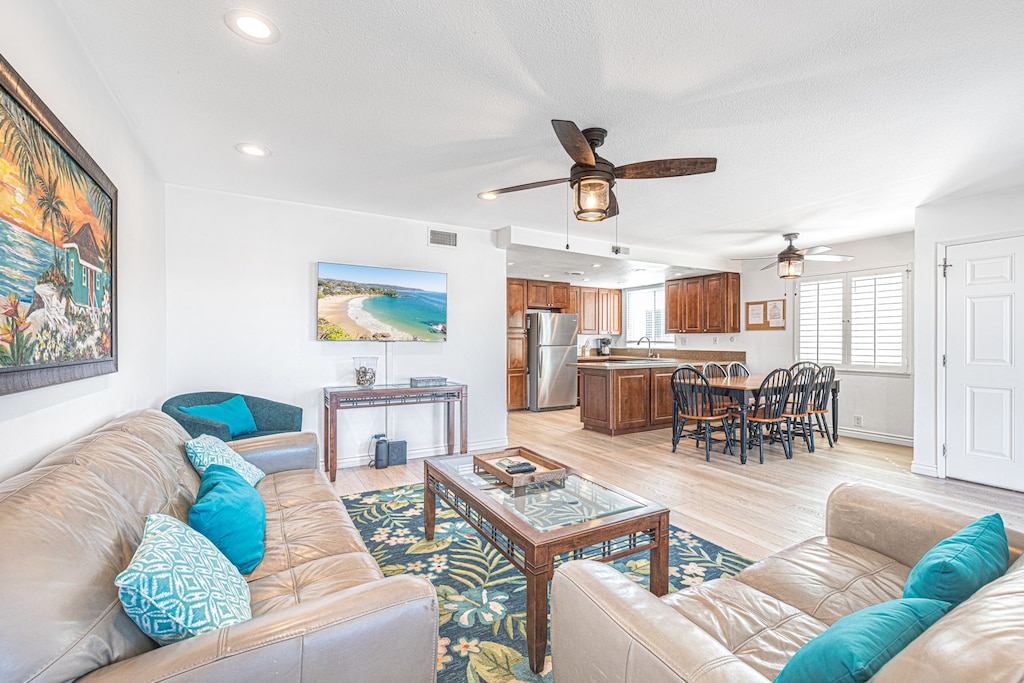 Main living and dining area with sliding glass doors to front ocean view balcony. Ceiling fans throughout.