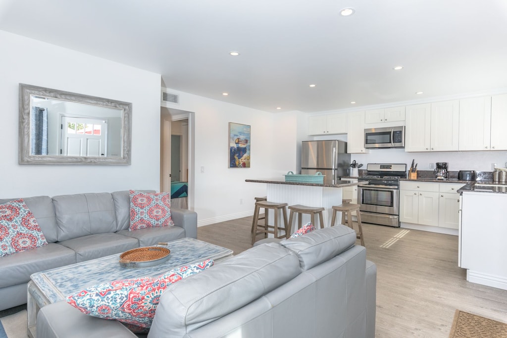 Front door opens up to the main living area, with a sofa set, cable TV, and open kitchen area.