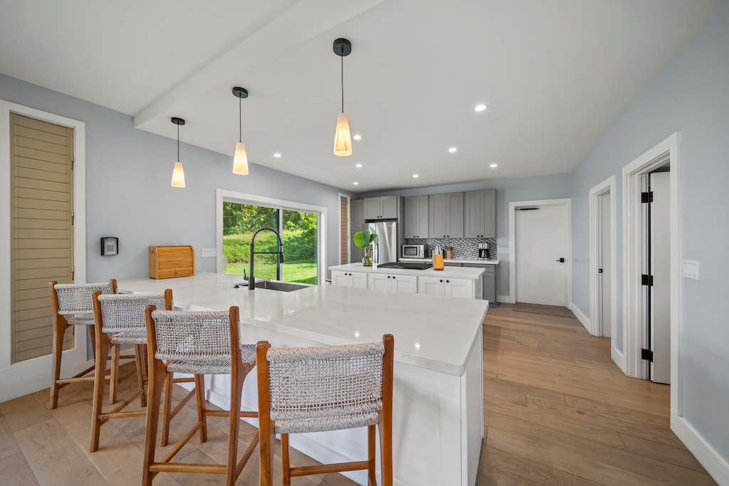 Gourmet kitchen pairs quartz island, gas range, and garden outlook.