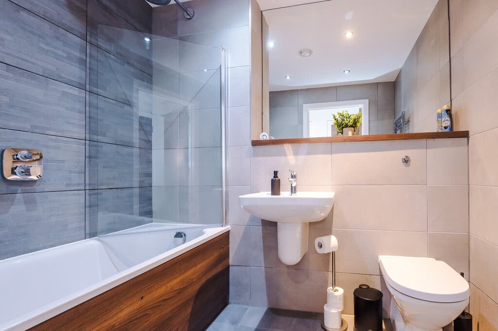 This full bathroom benefits from a toilet, sink, bath and overhead shower.