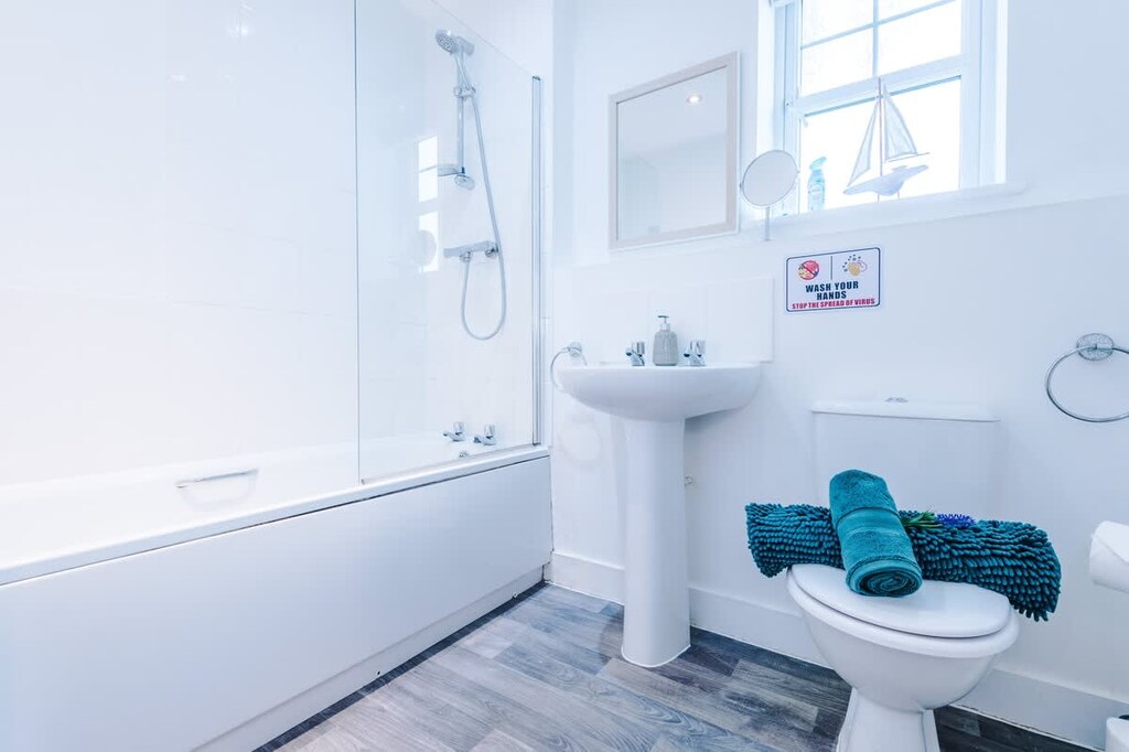 The first-floor bathroom benefits from a bath with an overhead shower, toilet and sink.