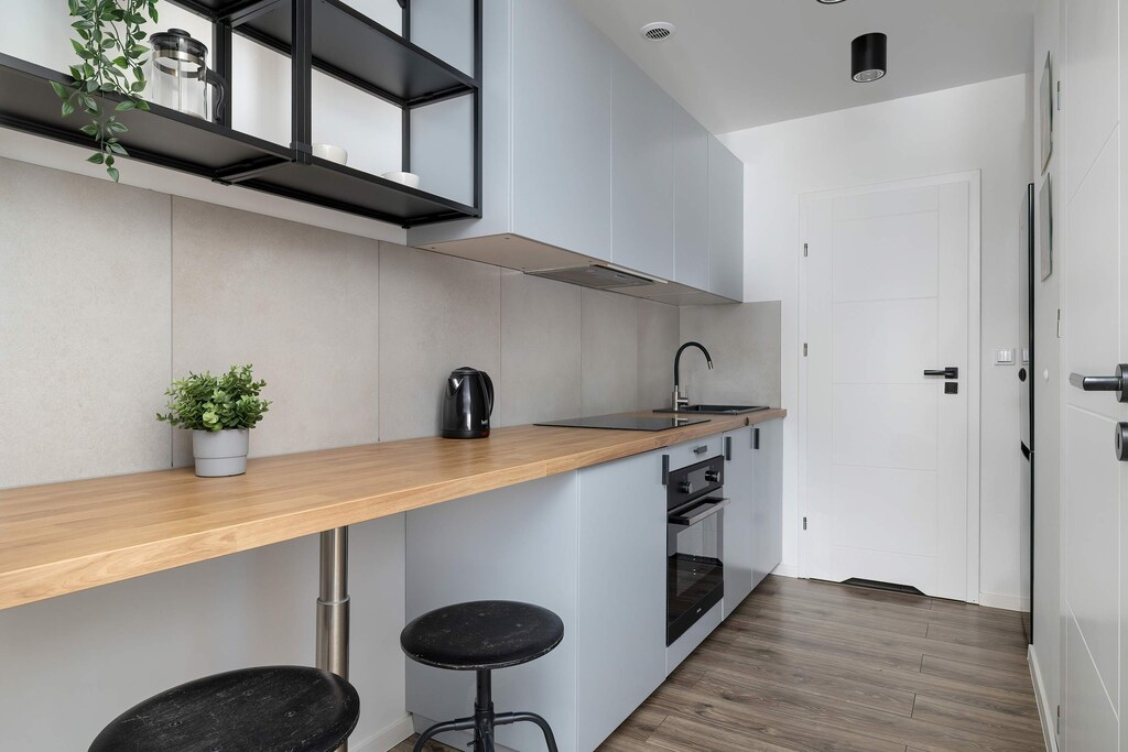 A modern kitchenette with sleek cabinetry and bar stools. The space is well-lit and functional, perfect for quick meals or morning coffee.