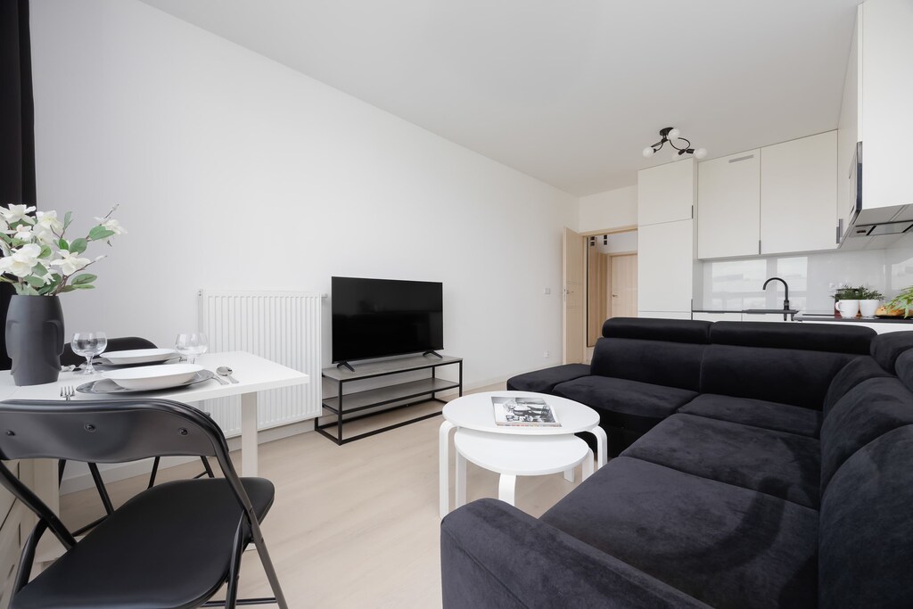 A modern sitting area with two dark sofas facing a flat-screen TV, next to a small circular coffee table.