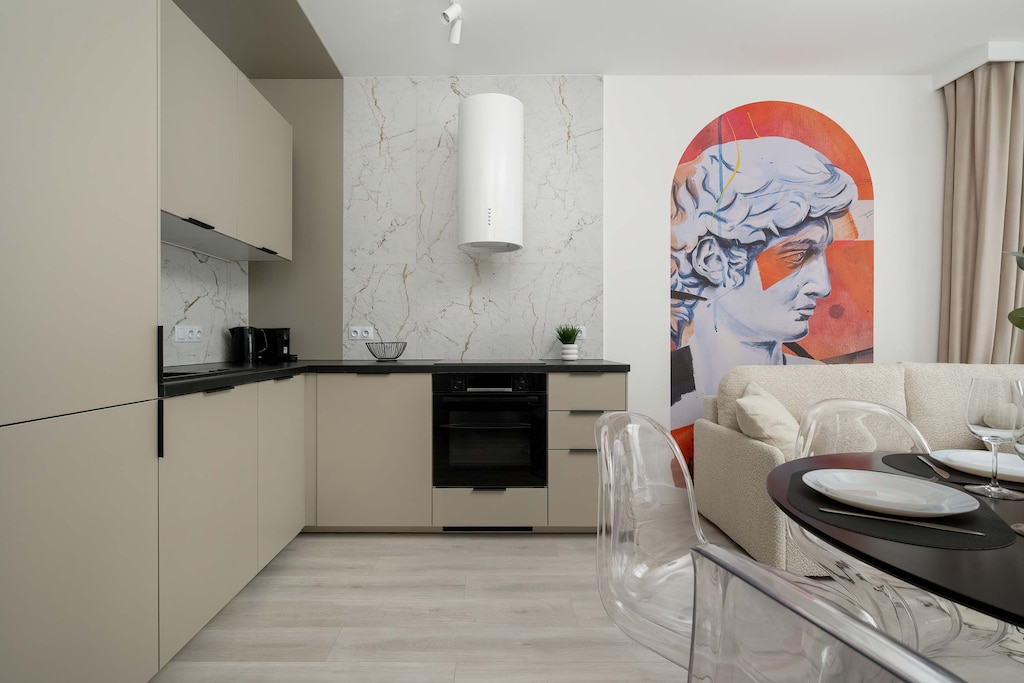 A functional kitchenette with cabinets, modern appliances (induction hob, oven, fridge with freezer, microwave, dishwasher) and a dining room with a round table and chairs.