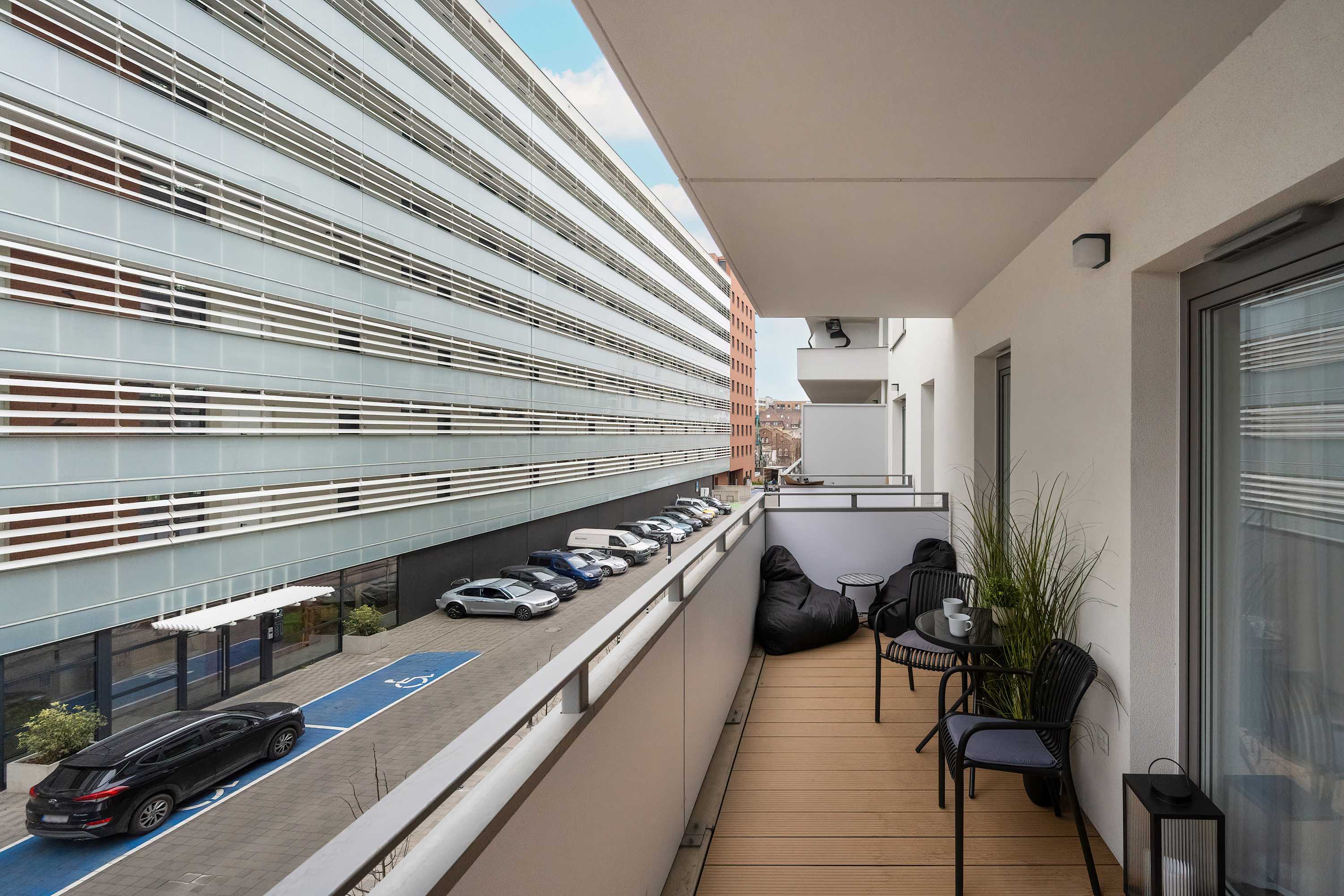 Balcony with wooden floor and glass balustrade, overlooking the surrounding buildings.