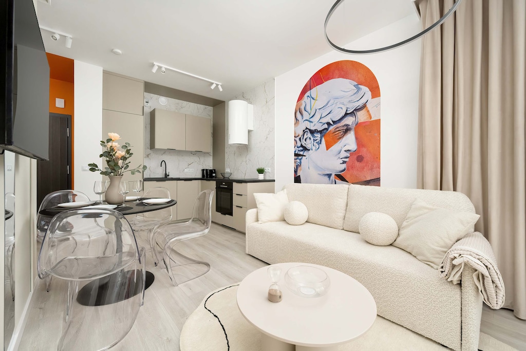 Modern living room with a round coffee table, a beige sofa and a kitchenette. 