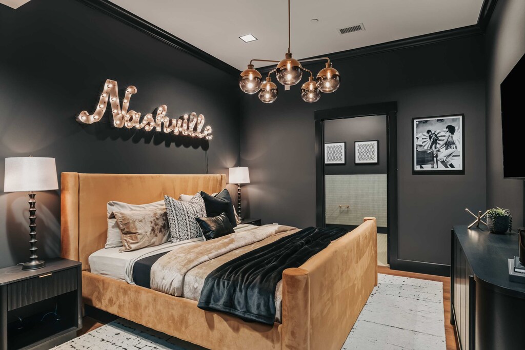 The king bedroom features rich crushed velvet accents, dark moody walls, and Nashville-inspired décor, creating a dramatic yet inviting retreat.
