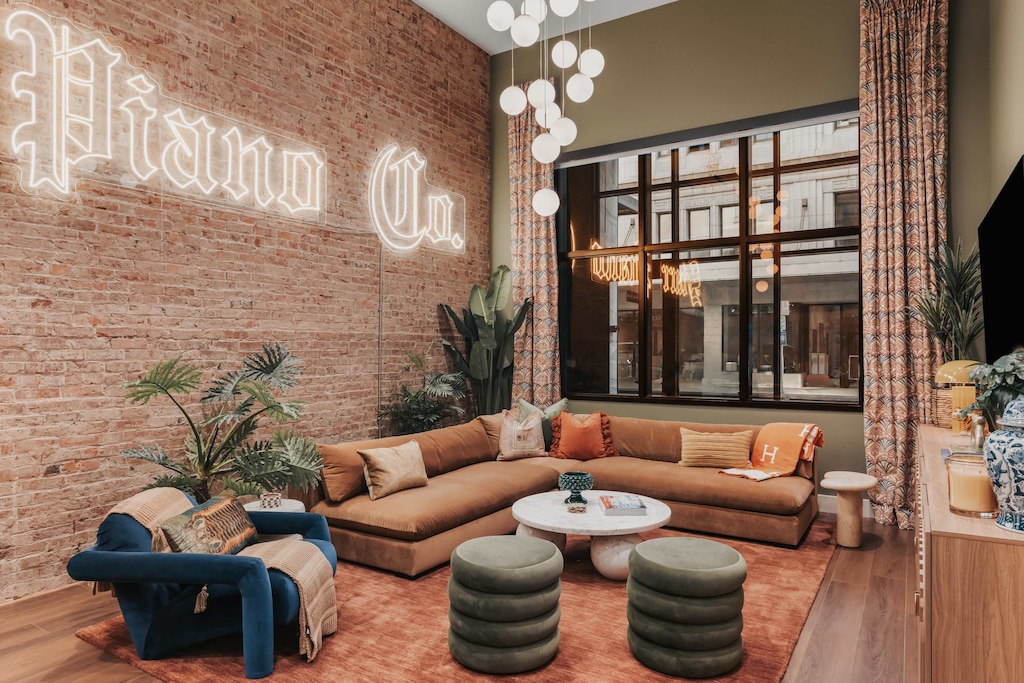 The living room boasts soaring vaulted ceilings, a plush oversized sectional, designer furnishings, and a sleek smart TV for elevated entertainment.