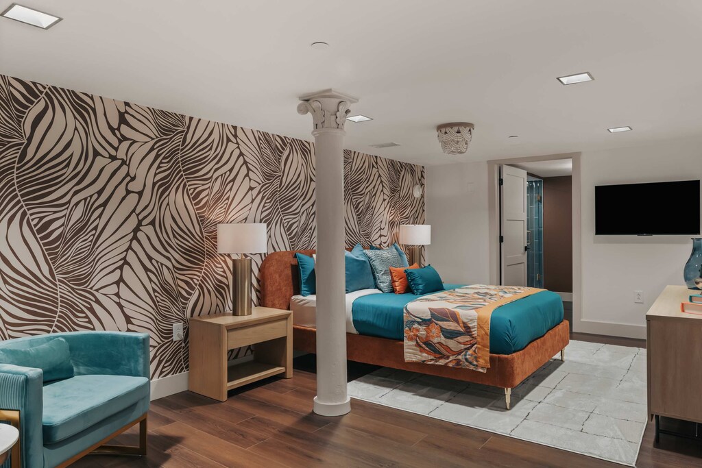 "The loft bedroom features a queen bed and overlooks the living room below, offering an airy, open feel. A smart TV adds modern convenience to this stylish retreat.