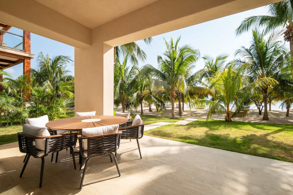 Terraza privada con comedor para 5 personas, con vista panorámica a jardín y acceso directo a la playa