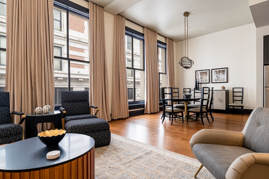 Open living area with high ceilings, floor-to-ceiling windows, and downtown views.