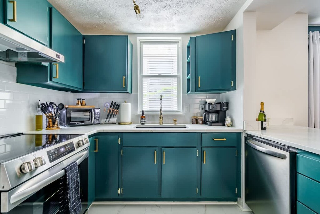 The rich teal cabinetry with gold hardware brings a luxurious and calming vibe to this stunning kitchen. 