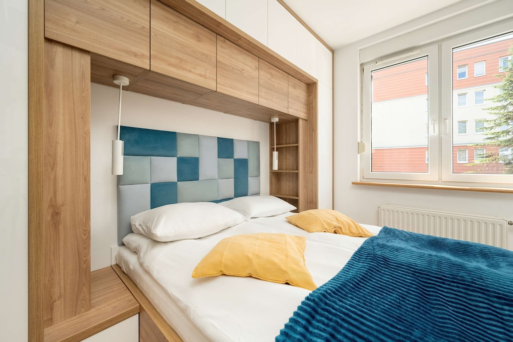 A bright bedroom with a modern headboard and blue-yellow accents invites rest and peaceful sleep.