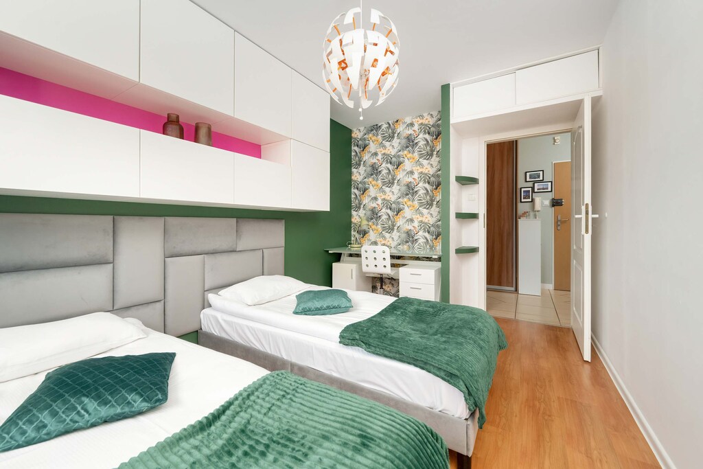 Two single beds with stylish lighting and green details create a comfortable space for both couples and friends.