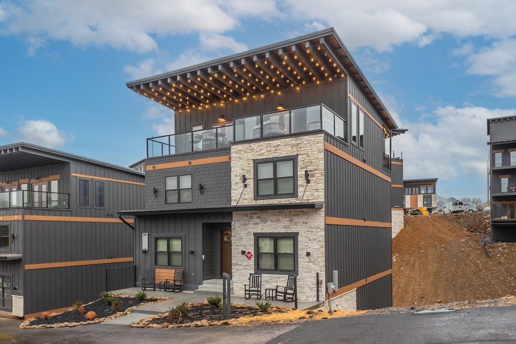A side view of a contemporary home with clean lines and large windows. The image highlights the spacious layout and the modern materials used in construction, showing a mix of stone and wood elements.