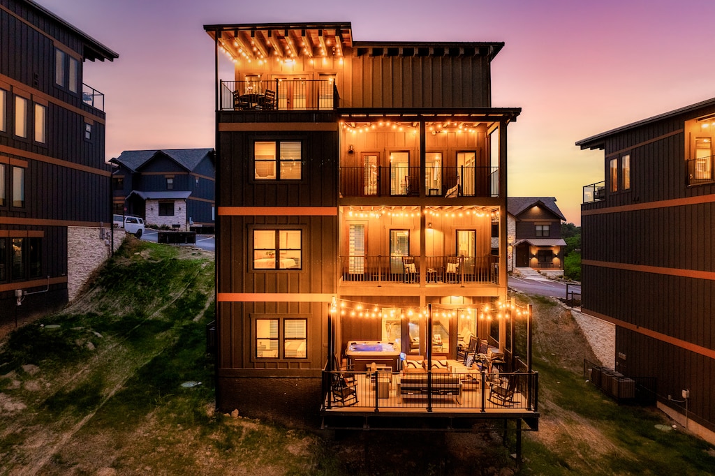 This image showcases a modern luxury Cabin at dusk, with large windows and a warm, inviting ambiance from the lights inside. The home has a multi-story design with a sleek, modern architectural style.