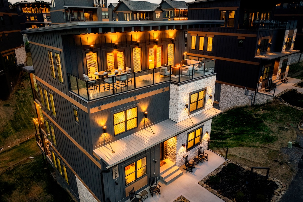 This nighttime view of a stylish, multi-story home with bright lights and elegant design features emphasizes the grandeur of the architecture, with well-lit outdoor spaces and a high-end finish.