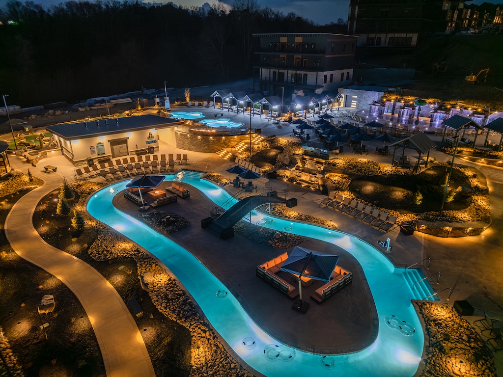 An aerial view of the resort’s lazy river at night, beautifully lit with glowing blue water and surrounded by cabanas and lounge chairs.