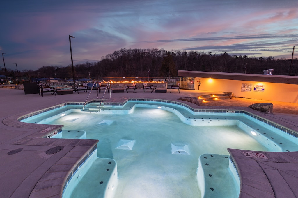 A small, intimate hot tub with glowing waters reflecting the colorful hues of the sunset, perfect for a romantic or relaxing soak.