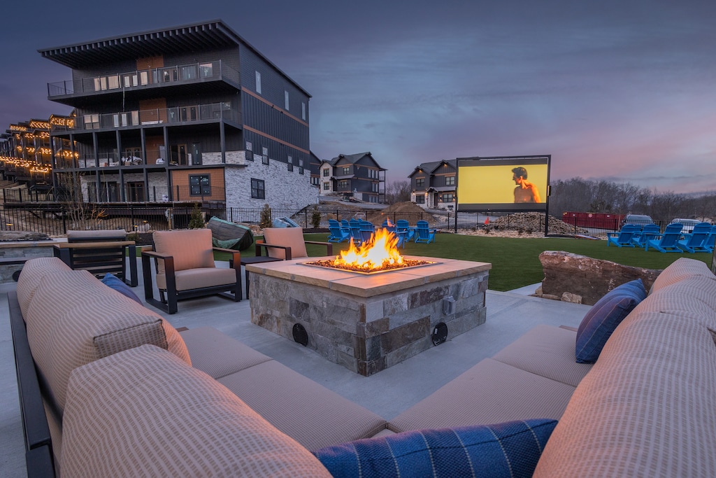 A luxurious fire pit seating area with cushioned chairs, overlooking the resort with a scenic mountain backdrop.