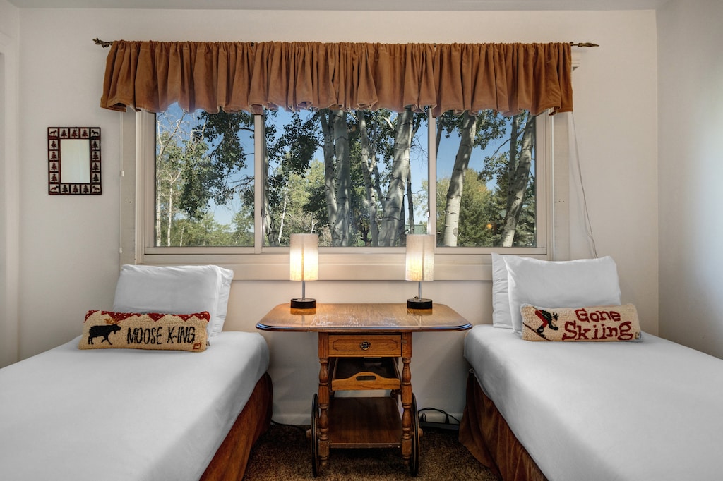The second bedroom offers two twin beds with ski pillows and crisp white bedding.