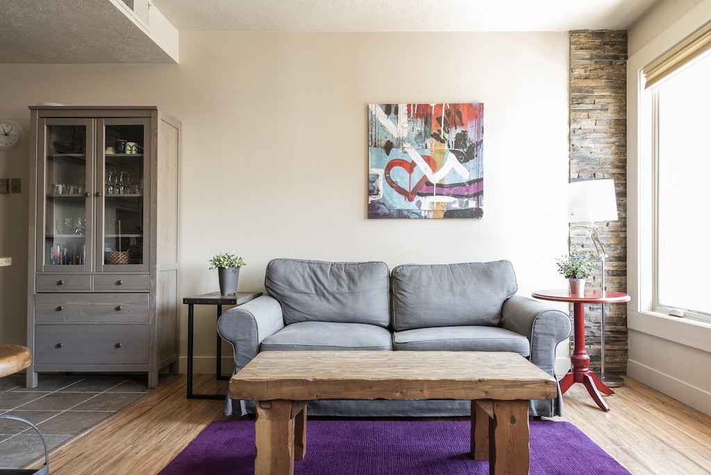 Grey sleeper sofa with modern colorful art piece in the living room and grey wood hutch with glass cabinets