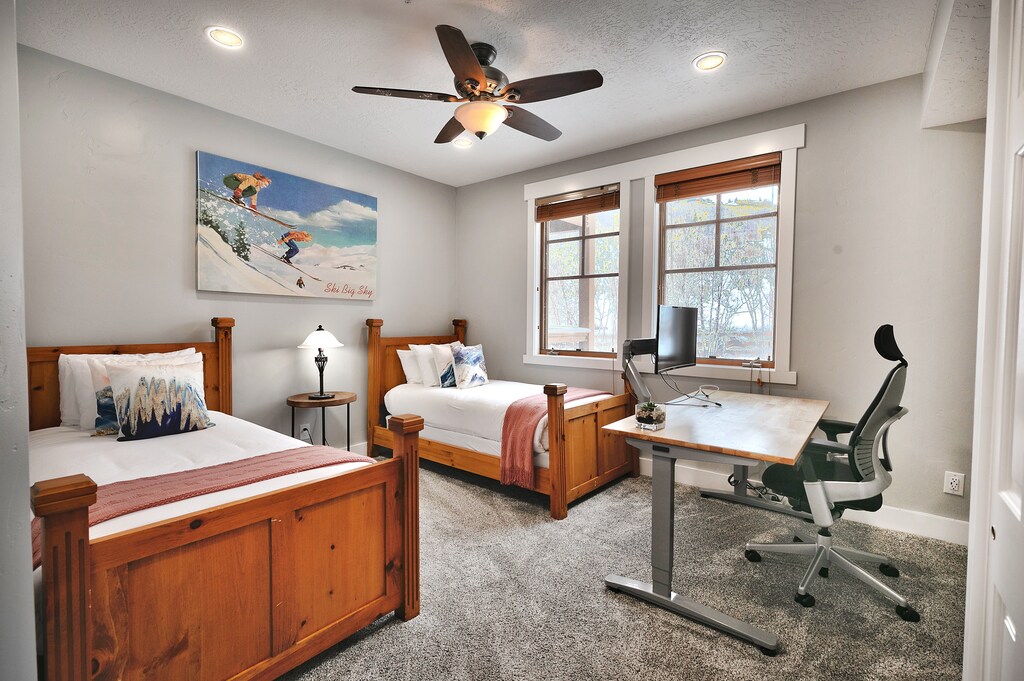 Two twin beds in the final guest bedroom, wooden bedframes and headboards, nostalgic ski art