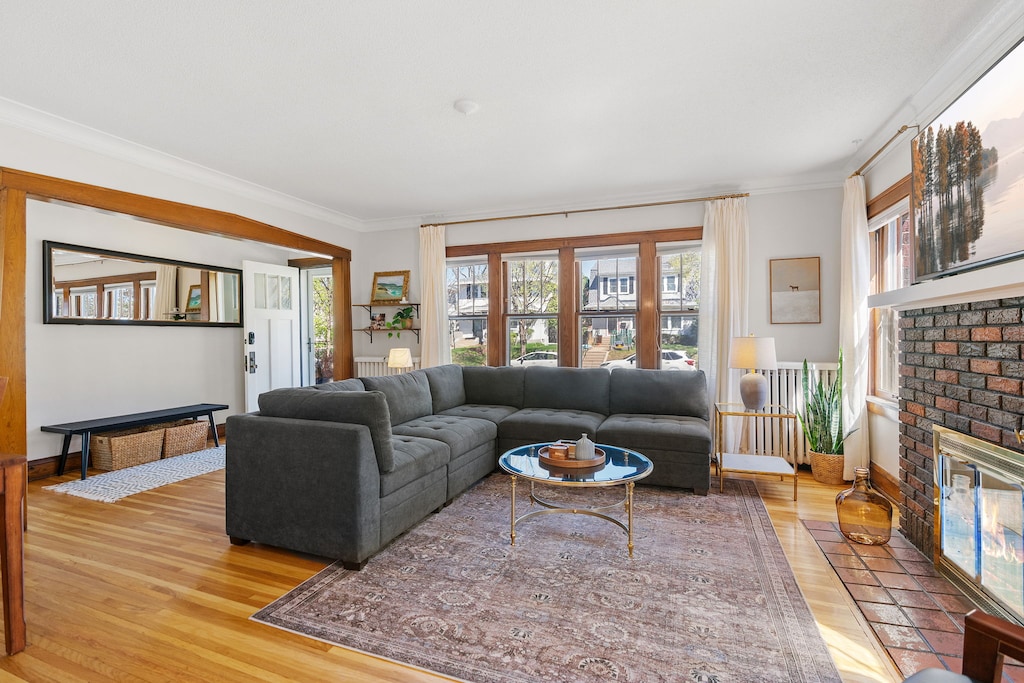 Relax in your spacious living room with plush sectional seating and warm brick fireplace, where natural light streams through charming windows.