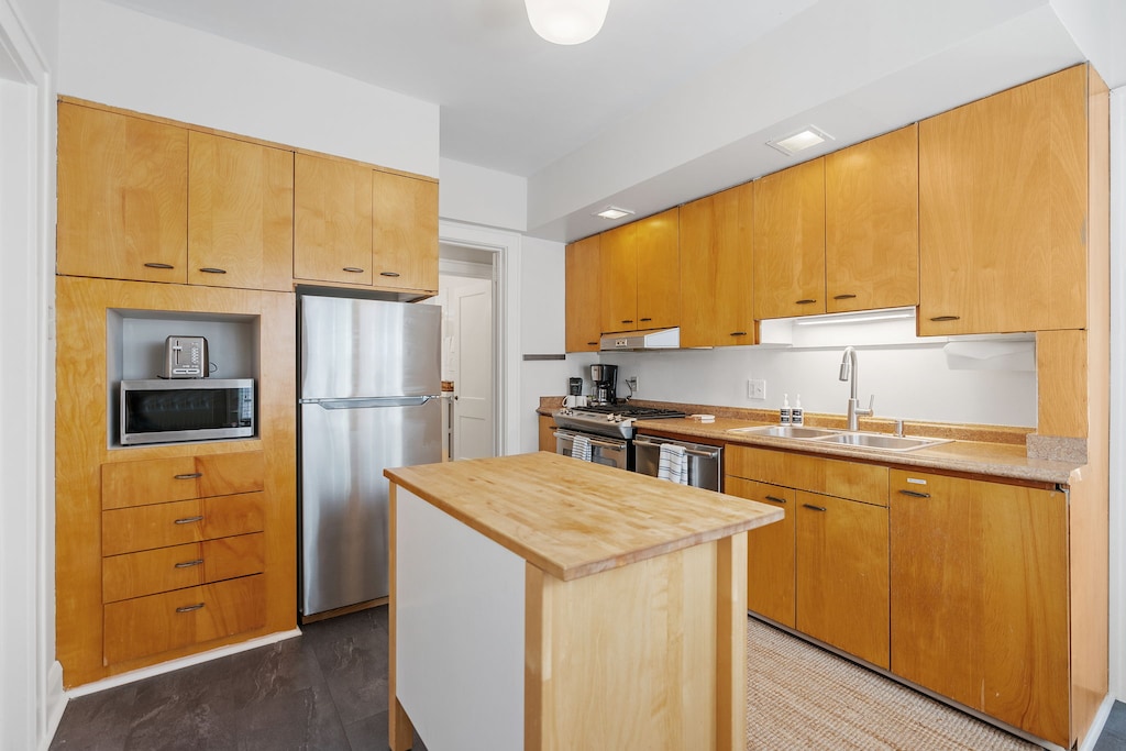 Your fully equipped kitchen features warm wood cabinetry, stainless appliances, and a convenient island perfect for meal prep and morning coffee.