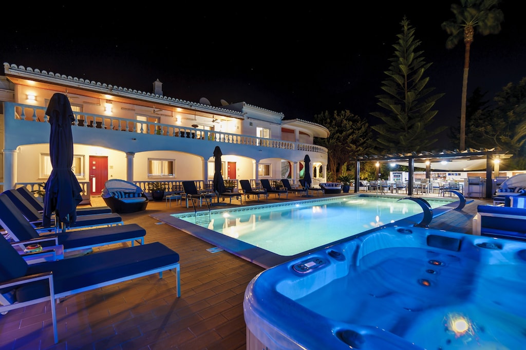 Sunlit terrace with pool, loungers, and hot tub