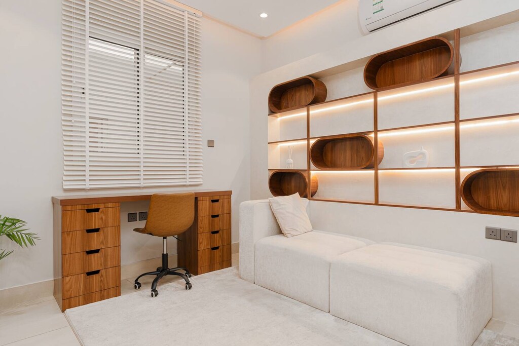 Bedroom with built-in desk and curved shelving perfect for work or study space.