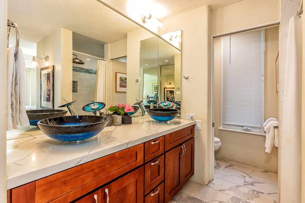 Freshen up in this beautifully designed bathroom with dual vessel sinks, elegant marble countertops, and bright natural light. Plush towels and artful touches make your morning routine feel like a retreat.