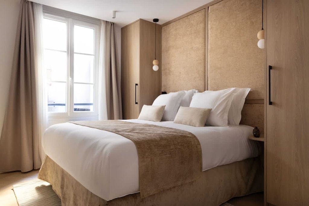 Une chambre parée d’un lit Queen size, d'une penderie, d'une TV et sa salle d'eau attenante équipée d'une douche et d'un lavabo.