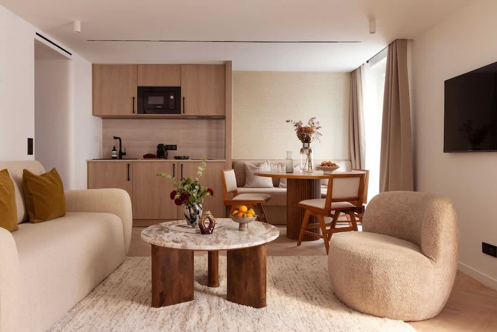 Une belle pièce à vivre dotée d'un canapé convertible, une table d'appoint, une table à manger et une TV.  Cuisine ouverte sur la pièce à vivre