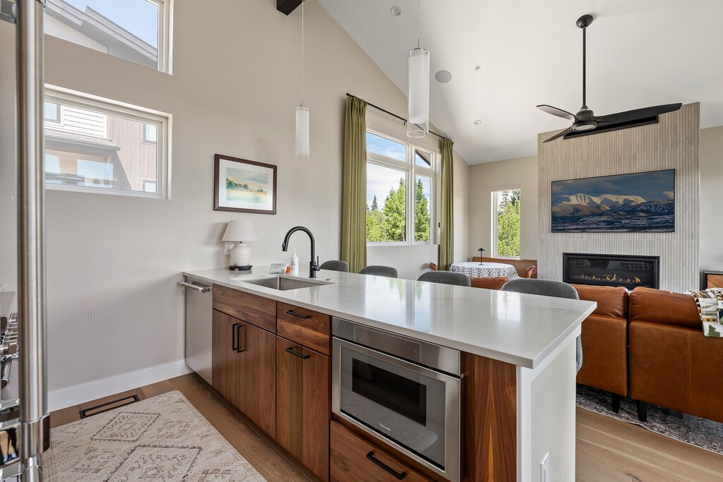 - Modern kitchen island with sink and built-in oven   - Open layout flows into living and dining area   - Bright windows fill the space with natural light