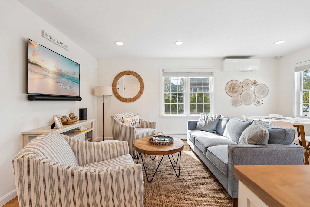 Living room with comfy couch, 2 chairs, and a large Smart TV