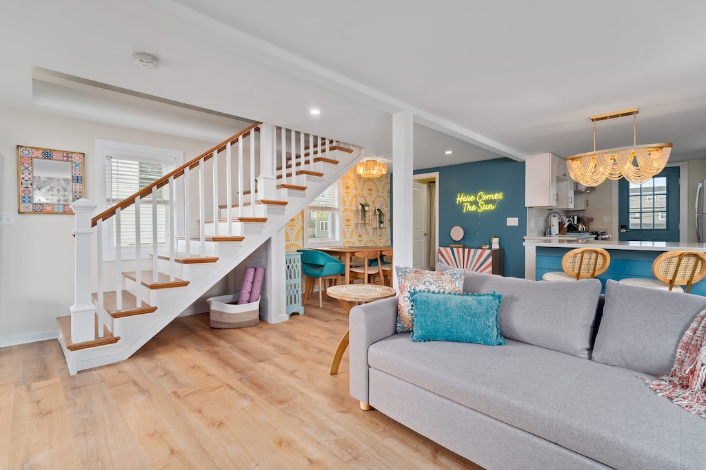 Open, living room, kitchen & dining room with "here comes the sun" neon light sign, flat screen smart TV & sleeper sofa. Private front covered deck with seating, back private deck with picnic table, yoga mats, dining table for 6 pp &  island for 2pp
