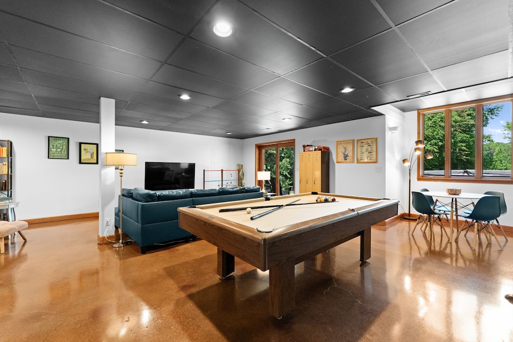 Game room with pool table, working space table, TV, and books, perfect for entertainment.