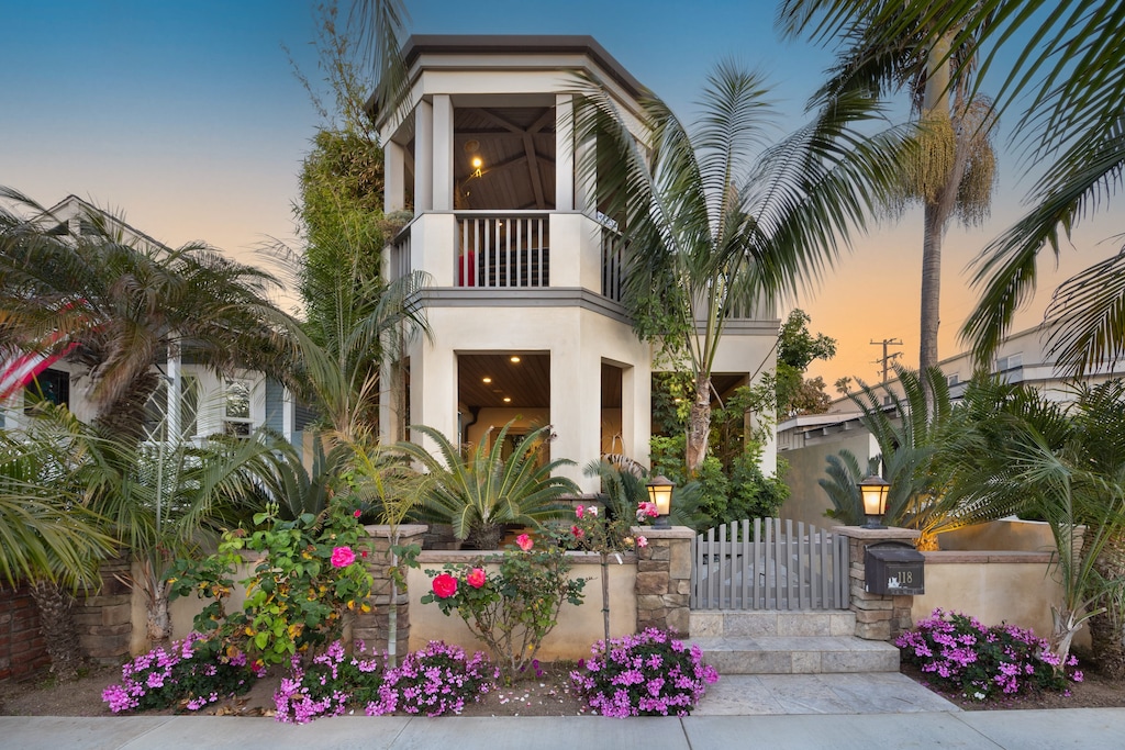 A picture-perfect exterior with lush palms and a golden sky.