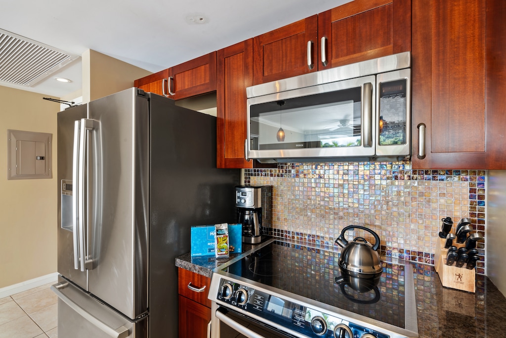 This kitchen in Honua Kai Konea 230/232 features a stylish backsplash and stainless steel appliances