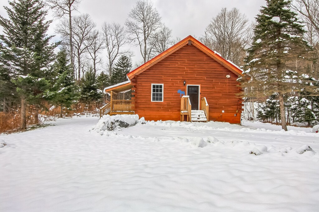 - Winter cabin exterior with wood siding design   - Snow covered surroundings create cozy escape   - Ideal retreat for relaxing mountain stays